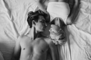 Motel para Casais em Campina Grande: O Refúgio Ideal 4 Intimate black and white photo of a young couple lying together on a bed, expressing closeness and romance.